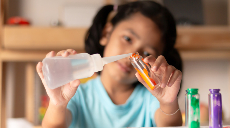 A Small Girl Pouring Chemical Solution Into A Beaker - Science Experiment Concept.