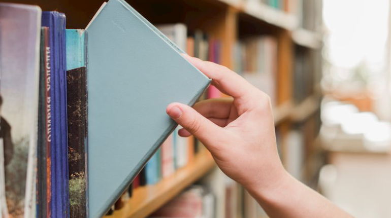 A Person Take Away A Book About Design & Technology From The Library Shelf.